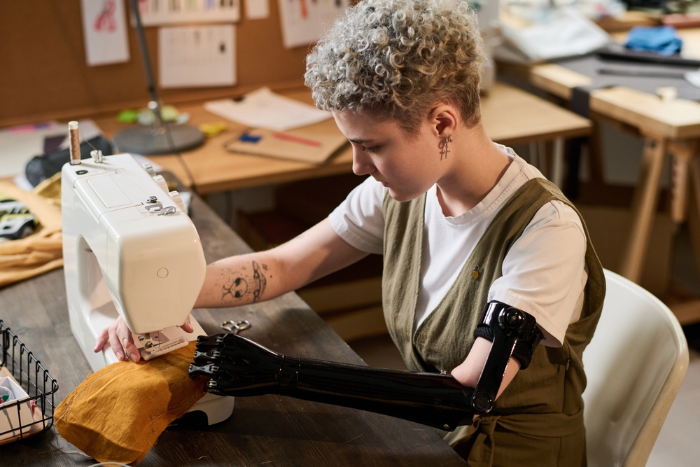 A self-employed seamstress with a prosthetic arm uses her sewing machine