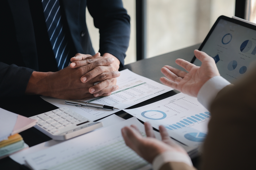 |A chartered accountant and client discussing their monthly managed accounts at a desk covered in documents